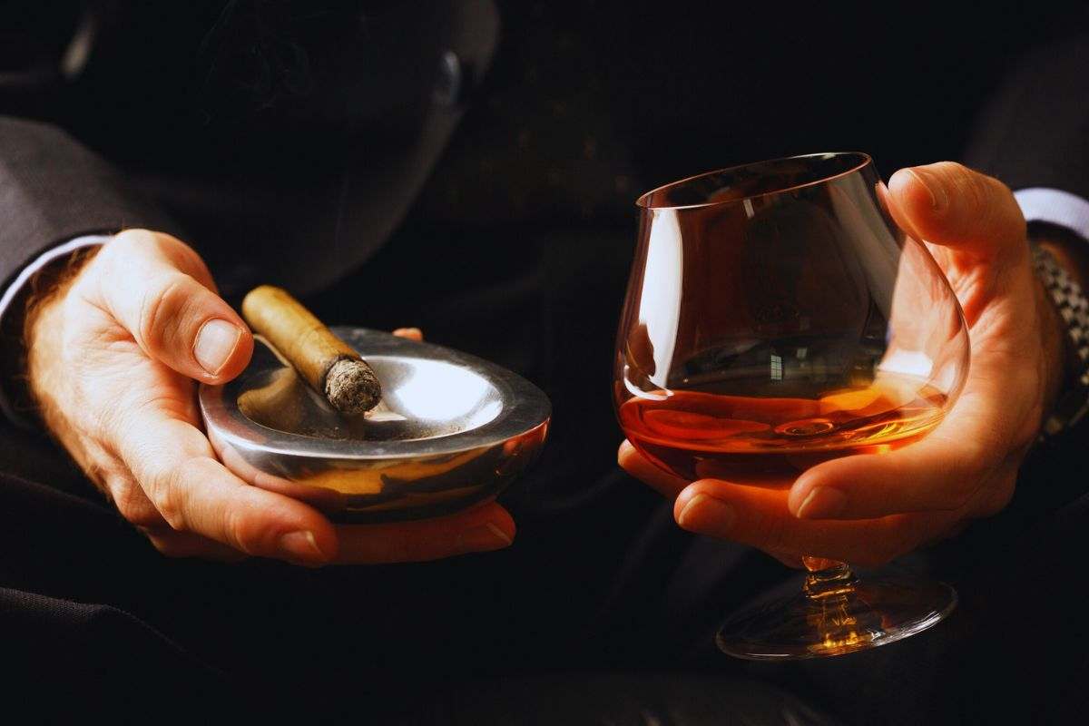 persona fuma sigaro e beve whiskey